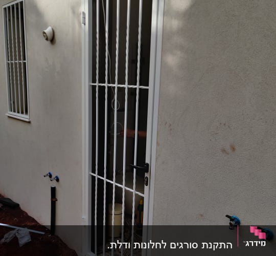 דלת עם סורגים לבנים על קיר חיצוני